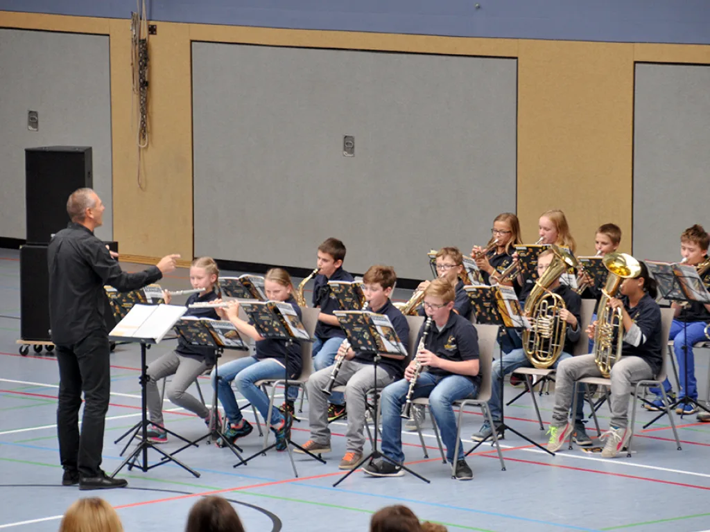 Das Blasorchester spielt an Notenständern in der Sporthalle.